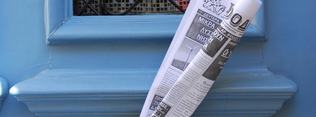 Blaue Holztüre und eine eingerollte Zeitung im Briefschlitz