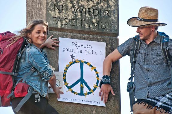 Zwei Pilger stehen vor dem dem Plakat "Friedenspilger"