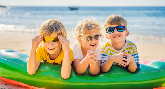 Foto von drei kleinen kindern am Stand auf einem Schlauchboot liegend